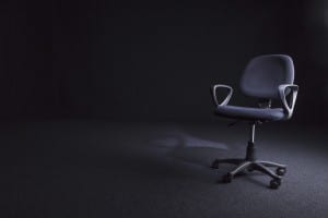 Shot of a worn office chair on a dark, cord carpet in a dark room - with plenty of copy space.